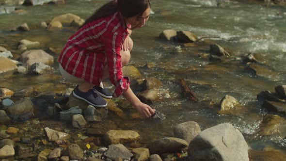 Lovely Cheerful Asian Woman Hiker Filling Travel Mug with Cold Fresh Water From Mountain River