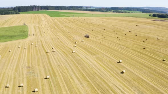 Aerial Drone Shot  a Field with a Tractor and Hay Bales in a Rural Area on a Sunny Day