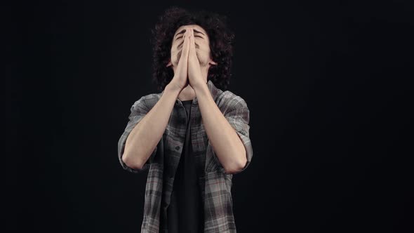 The Charismatic Young Man Impatient Prays with His Eyes Closed and Crosses His Fingers for Good Luck
