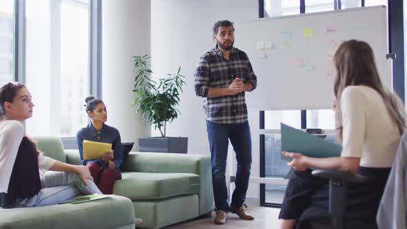 Diverse group of business colleagues brainstorming using whiteboard in meeting room