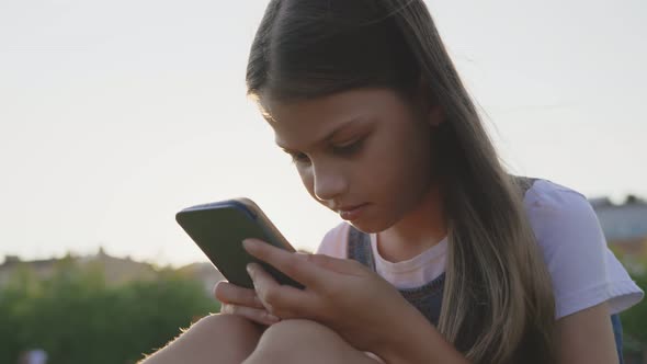 Close Up Portrait of Preteen Girl Using Smartphone in Park