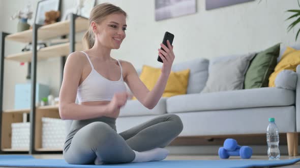 Woman Talking on Video Call on Smartphone While Sitting on Yoga Mat