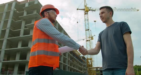 Architect Contractor Shaking Hands with Client at Construction Site.