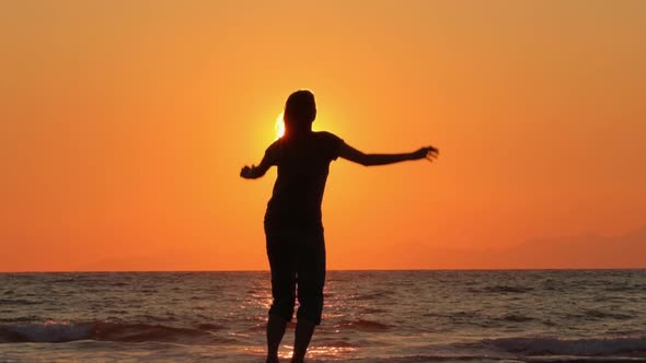 Happy Woman Jumping on a Beach at Sunset