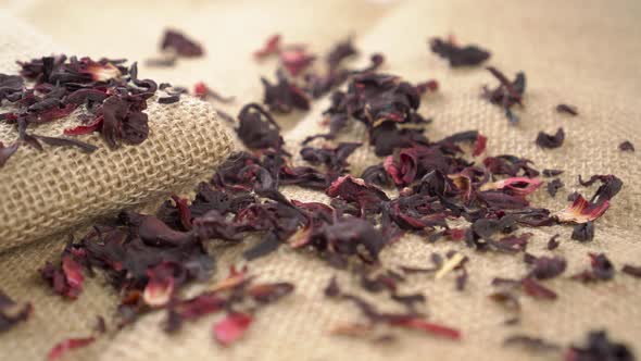 Dried tea hibiscus petals on a rough rustic burlap close up