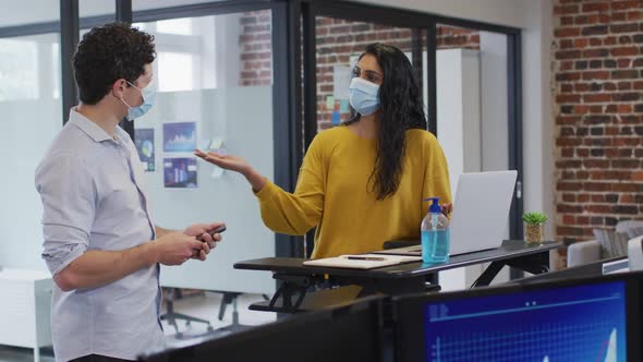 Man and woman wearing face masks working together in office