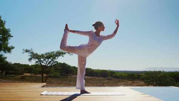 Woman performing yoga near poolside