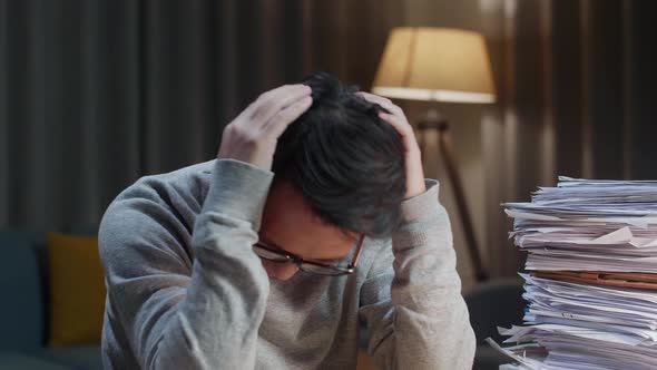 Close Up Of Asian Man Throwing Paper And Having Headache While Working Hard With Documents At Home