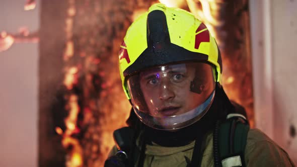 Potrait of Young Firefighter in Full Uniform in Front of Burning House