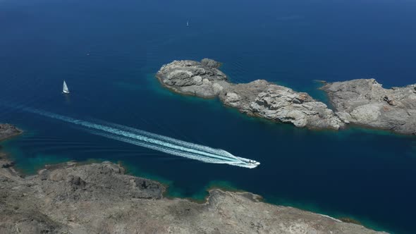 Aerial View of Boat Sailing Along Rocky Sea Coast