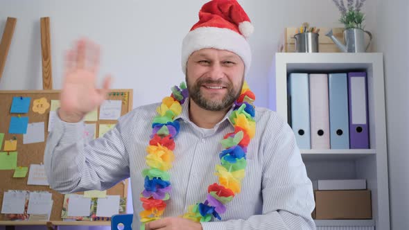 Middle aged man in a Santa hat smile at the camera and say hallo. Christmas Videocall