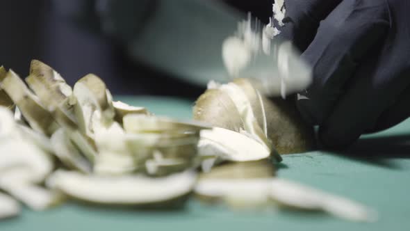 Cook's Hands in Black Gloves Slicing Mushrooms Selective Focus