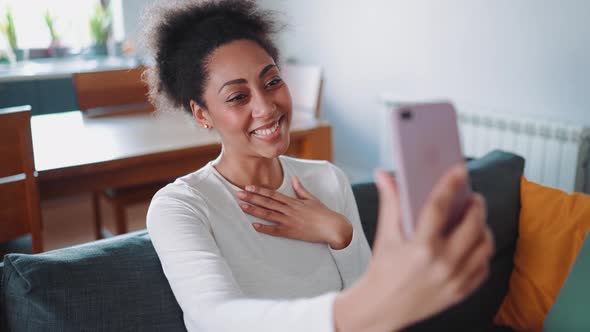 Cute African pregnant woman talking by video call on phone