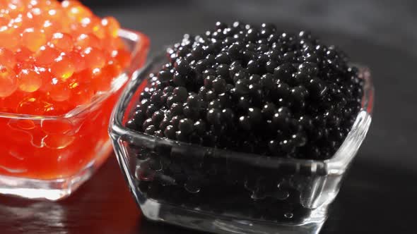 Red and Black Caviar Rotated Over Black Background. Close-up Salmon Caviar Rotation. Delicatessen.