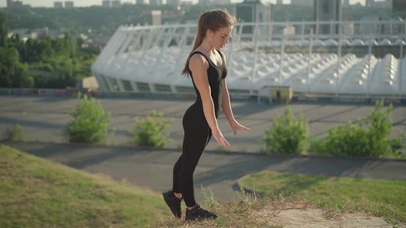 Performance of Slim Gymnast at Sunrise with Urban City at the Background. Wide Shot Portrait of