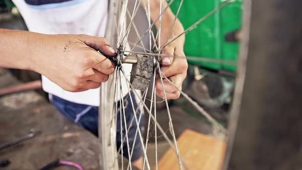 Teenage Boy Repairing the Wheel of His Bicycle in a Workshop in a Close Up View on His Hands