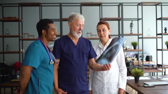 Good Looking Multiethnic Group of Doctors Discussing History of Disease Using X-ray or MRI Scan.