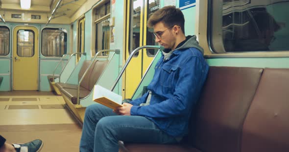 Brutal Guy in Jeans is Reading a Book in an Empty Carriage