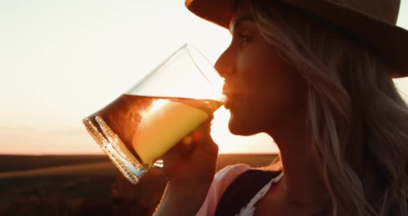 Cowgirl in Hat Drinks a Pint of Beer and Has Pleasure on Dazzling Background