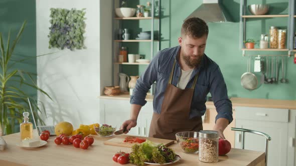 Man Talking By Phone and Use Laptop While Cooking Breakfast