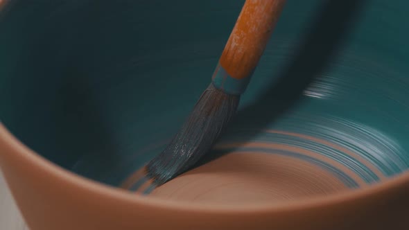 Painting a Pot in Blue Color Using a Brush