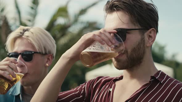 Two young caucasian men having fun on music festival while drinking beer. Shot with RED helium camer