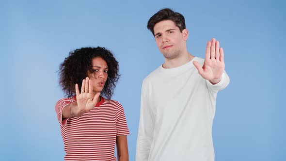 Interracial Serious Couple Showing Rejecting Gesture By Stop Palm Hand Sign