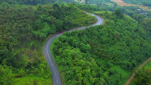 Aerial view over a winding road in the mountains of a tropical forest, Thailand.