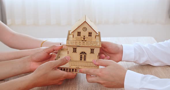 Real Estate Agent Holding Home Miniature To His Client