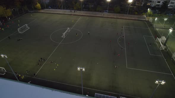 Aerial View of Soccer Pitch at Night with Amateur Football Players Playing the Game in the City