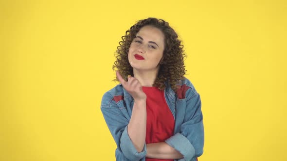 Girl Listens Carefully, Threatens with a Finger and Waves Her Head Negatively on Yellow Background