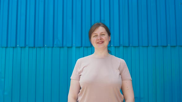 Young Positive Woman Confidently Shows Thumbs Up Gesture Near Blue Ribbed Wall