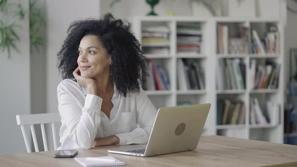 Portrait of Young African American Woman Dreaming About Something Pleasant and Smiling