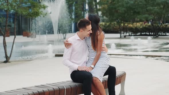 Beautiful Black Girl Sitting on Her Boyfriend's Knees and They Hugging Outdoors