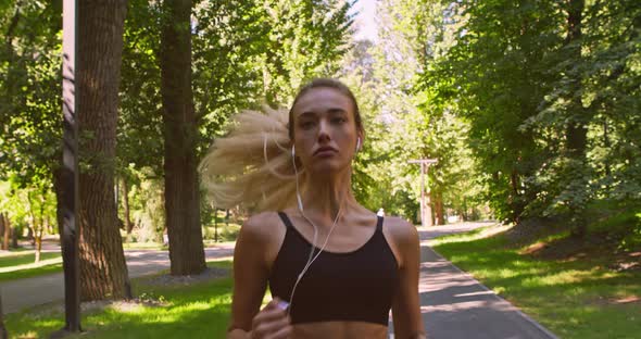 Millennial Woman Practicing Run Workout in Park, Listening To Motivational Music