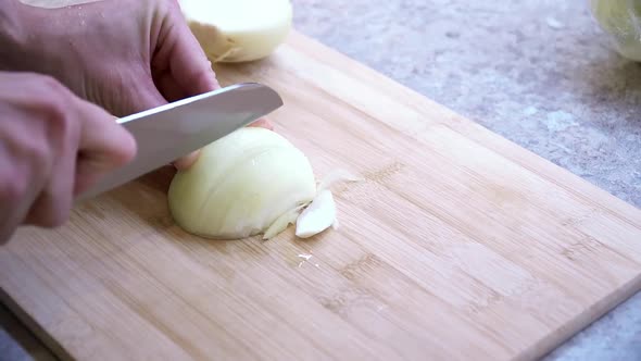 Close-Up of the girl cuts onions on a wooden cutting board