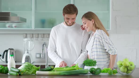 Healthy Food Young Couple Prepares a Salad in the Kitchen Man and Woman Cuts Herbs and Green