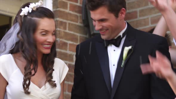 Slow-motion bride and groom under thrown rice.