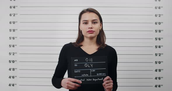 Mugshot of Young Attractive Woman with Holding Sign for Photo in Police Department