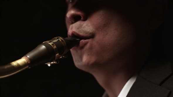 Man Musician Blows a Closeup of the Saxophone in Darkness