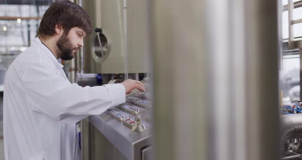 A Male Brewer with a Beard at Brewery Factory Working Behind the Control Panel Dashboard