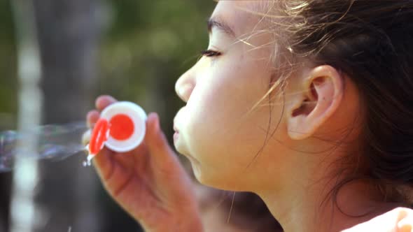 Close-up of schoolgirl playing with bubble wand in playground