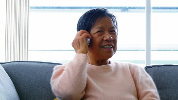 Senior woman talking on mobile phone in living room