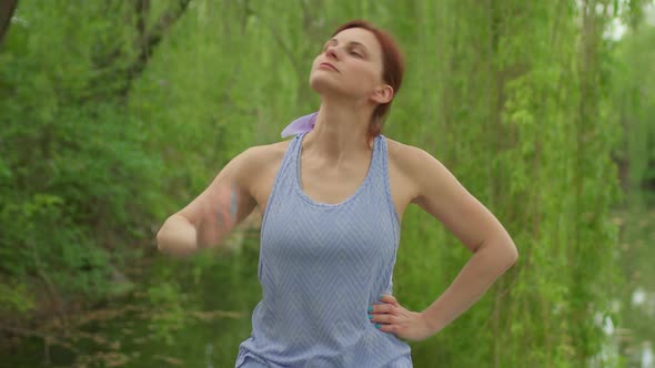 30s Woman in Sportswear Doing Stretching Exercise for Her Heck Outdoors