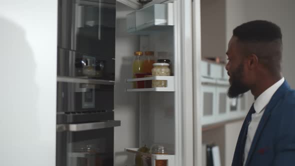 Handsome African Businessman Opening Fridge and Taking Bottle of Juice