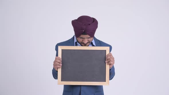 Happy Bearded Indian Sikh Businessman Thinking While Holding Blackboard