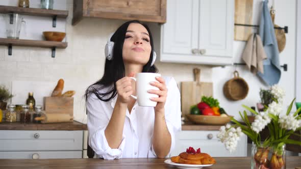 Young Woman Listening To Music With Headphones At Home With Cup Of Coffee