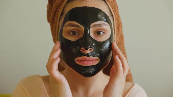 Girl with Black Cosmetic Mask Looking at Camera Touches Her Mask with Her Hand