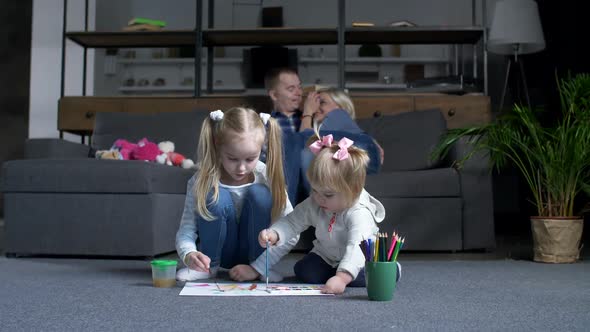 Little Girls Painting While Parents Resting on Sofa