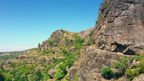 Low Flying Aerial Shot Rocky Cliffs In Mountain Valley In Summer Vibrant Day